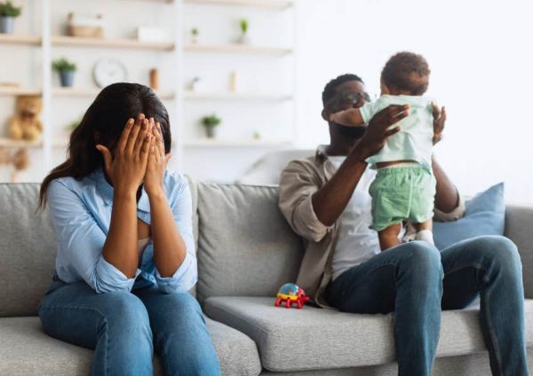 tired mom crying while dad plays with baby