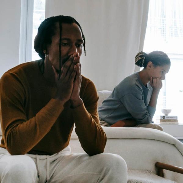 couple sitting on opposite sides of the bed after arguing