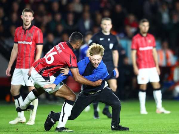 Walsall midfielder Ronan Maher tackles a pitch invader on September 24, 2024