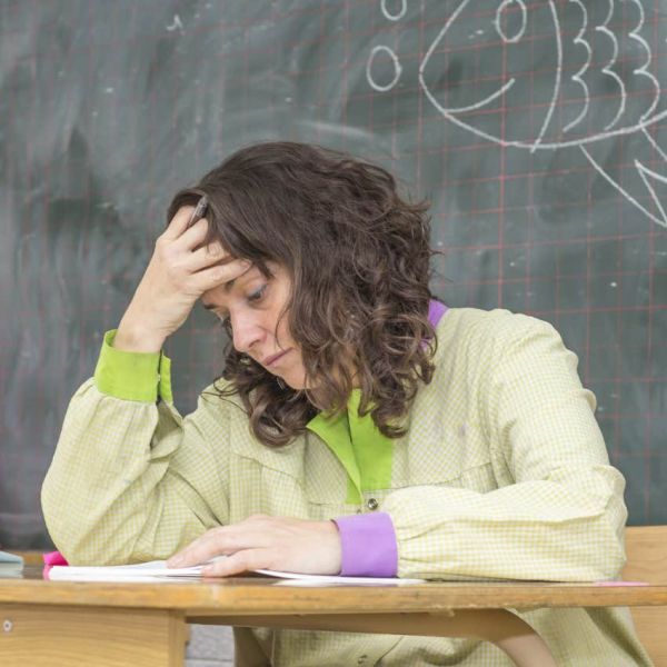 Teacher looking stressed sitting in her classroom. 