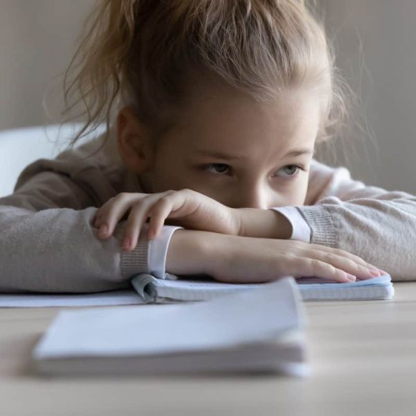 sad little girl resting head on desk