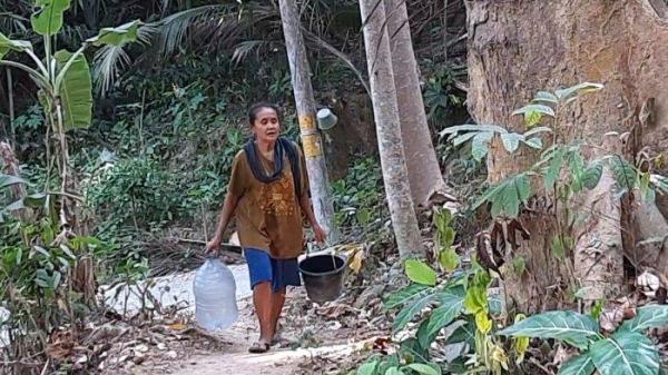 Marsinem, warga Padukuhan Sangon I, Kalurahan Kalirejo, Kapanewon Kokap, Kulon Progo, saat mengambil air dari sumur yang mengering pada Kamis (17/10/2024).