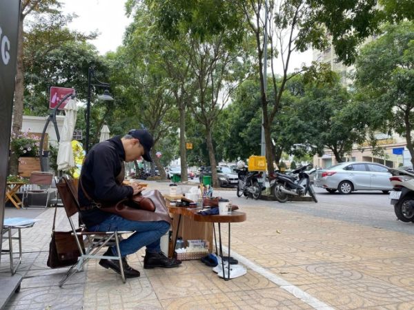 Mr. Phong shines shoes in front of a cafe on the street, during a difficult time due to the Covid-19 outbreak, in 2021. Photo: Khoi Nguyen