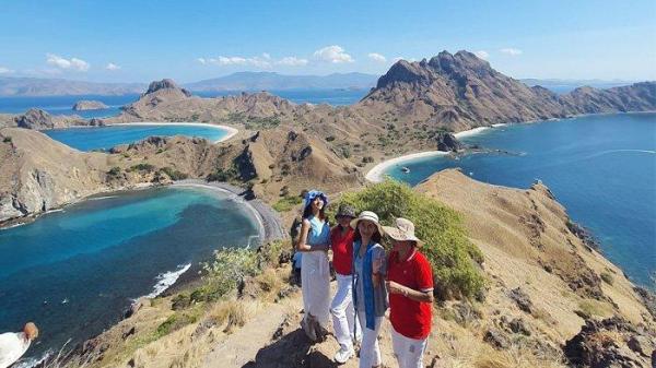 Para pengunjung berpose dengan latar belakang pemandangan Pulau Padar di Taman Nasional Komodo, Kabupaten Manggarai Barat, NTT.