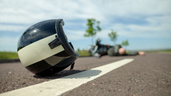 A black and white helmet on the ground behind a crashed motorcycle