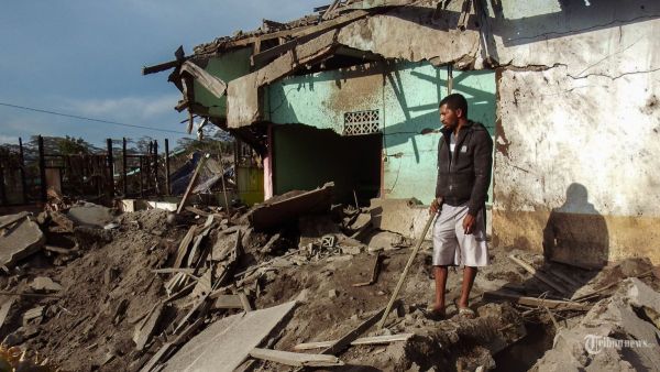 Seorang warga melihat rumah yang hancur sehari setelah erupsi Gunung Lewotobi Laki-Laki di Desa Hokeng Jaya, Flores Timur, Nusa Tenggara Timur, pada 5 November 2024. (Photo by ARNOLD WELIANTO / AFP)