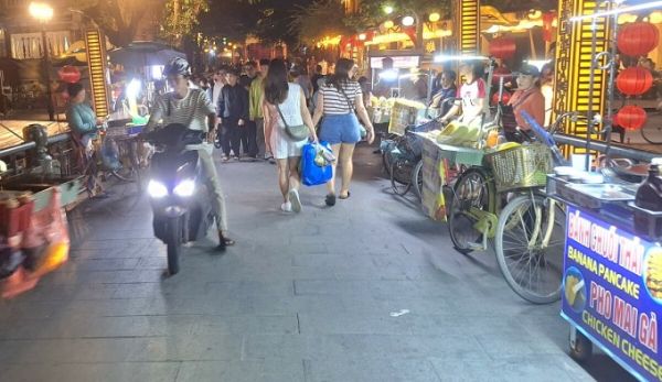 Street vendors stand along the area near An Hoi Bridge in Hoi An, November 2024. Photo by Hoang Vu