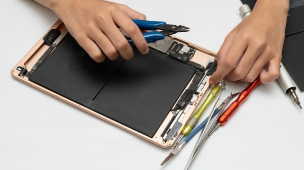 iPad undergoing repairs, with multiple tools.