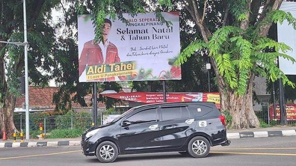 Kendaraan roda 4 saat melintas di depan beliho bergambar Aldi Taher yang terpasang di Simpang lampu merah Tranasmart, Kota Pangkalpinang pada Kamis (26/12/2024).