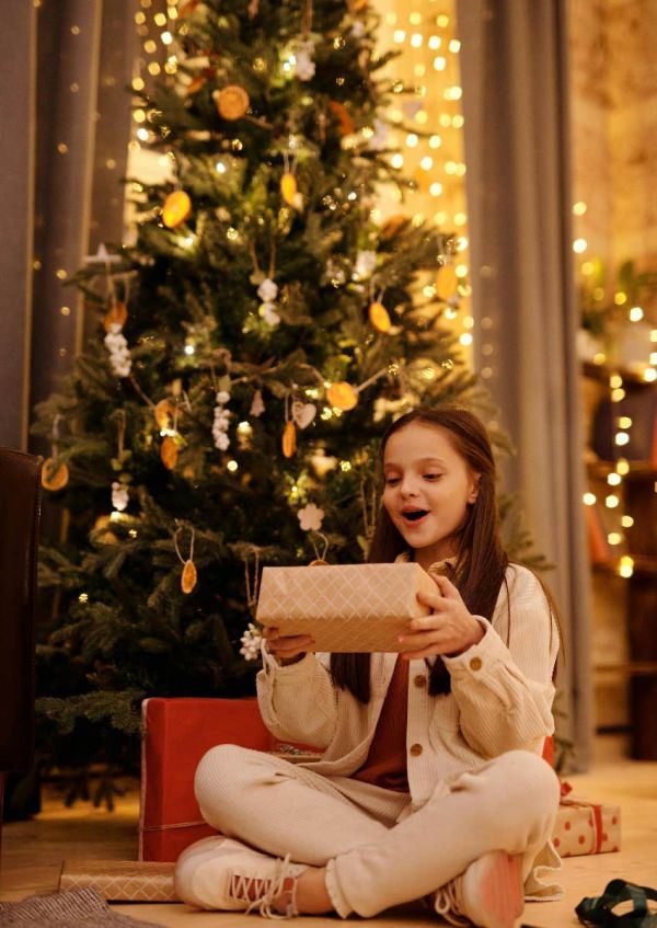 little girl opening presents by the Christmas tree