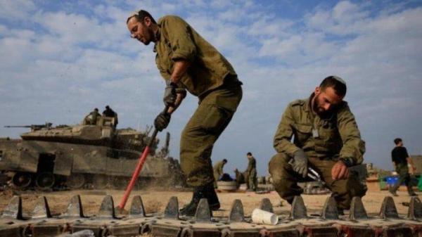 Dua serdadu Israel (IDF) tampak membetulkan rantai tank tempur yang bermasalah. Perang banyak front yang berlarut secara nyata menguras ekonomi Israel sebagai dampak dari beban perang.