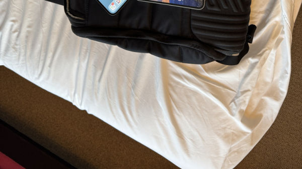 Backpack with laptop and two smartphones on top of a bed