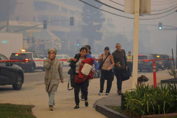 Orang-orang mengungsi, saat kebakaran hutan terjadi di dekat Pacific Palisades selama badai angin yang dipicu oleh cuaca di sisi barat Los Angeles, California, Selasa (7/1/2025). Foto: Mike Blake/REUTERS