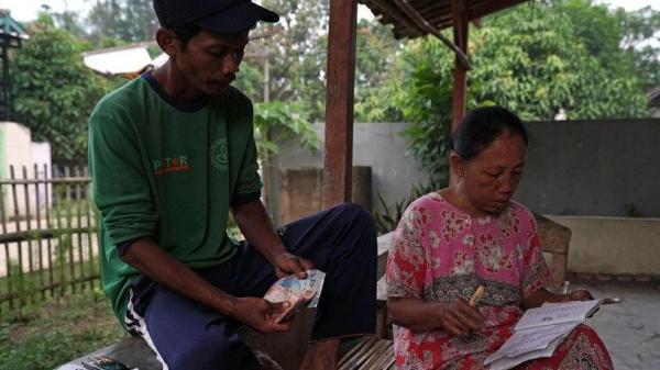 Seorang petani dan istrinya sedang mencatat keuangan mereka. 