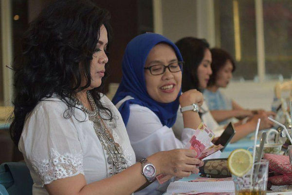 Seorang wanita sedang menghitung uang saat arisan di Jakarta. 