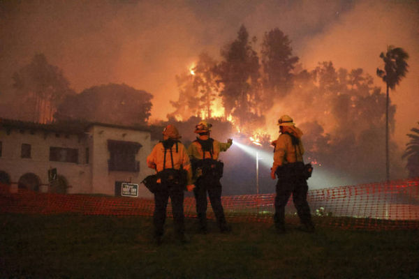 Petugas kebakaran setempat memadamkan api di perbukitan yang menghadap ke lingkungan Hollywood di Los Angeles, California, Amerika Serikat, Rabu (8/1/2025). Foto: David Swanson/REUTERS