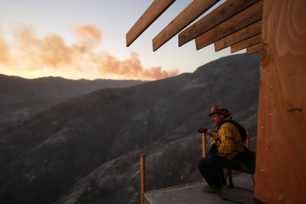 Seorang petugas pemadam kebakaran beristirahat saat petugas memadamkan Kebakaran Palisades di Mandeville Canyon, Sabtu (11/1/2025). Foto: Eric Thayer/AP Photo