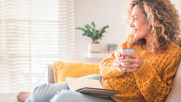 observant woman sitting on couch holding coffee