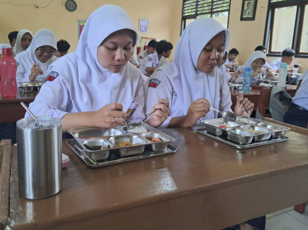 Siswa menyantap makanan saat Menteri Pendidikan Dasar dan Menengah Abdul Mu'ti memantau pemberian makan bergizi gratis di SMP 12 Semarang, Senin (6/1/2025). Foto: Intan Alliva Khansa/kumparan