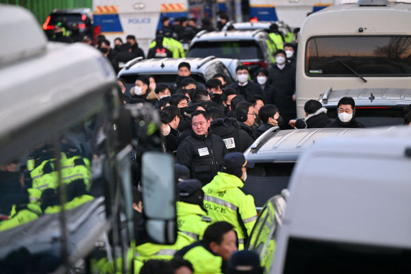 Polisi dan penyelidik tiba di kediaman Presiden Korea Selatan yang dimakzulkan Yoon Suk Yeol di Seoul pada 3 Januari 2025. - Penyelidik Korea Selatan tiba di luar kediaman presiden pada Jumat pagi untuk menangkap Yoon Suk Yeol, dan para pendukung setia pemimpin yang dimakzulkan itu berkumpul. di luar untuk melindunginya, wartawan AFP melihatnya. Mobil-mobil yang membawa penyelidik yang menyelidiki deklarasi darurat militer Yoon yang berumur pendek melaju ke kediamannya di pusat kota Seoul, yang dikelilingi oleh banyak polisi, AFP melihat. Yoon akan menjadi presiden pertama dalam sejarah Korea Selatan yang ditangkap. (Photo by JUNG Yeon-je / AFP)