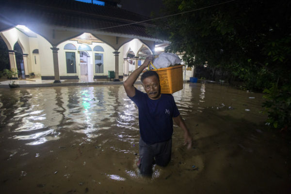 Warga membawa barang untuk mengungsi saat terjadi banjir di kecamatan tengahtani, Kabupaten Cirebon, Jawa Barat, Sabtu (18/1/2025). Foto: Dedhez Anggara/ANTARA FOTO