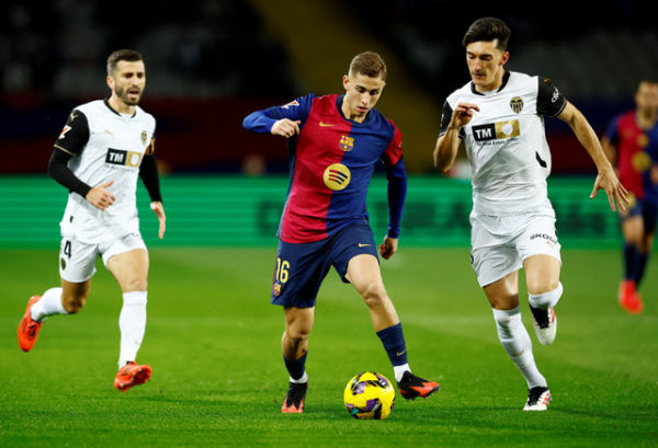 Aksi Fermin Lopez (tengah) saat Barcelona vs Valencia dalam laga pekan ke-21 Liga Spanyol 2024/25 di Estadi Olimpic Lluis Companys, Senin (27/1) dini hari WIB. Foto: REUTERS/Albert Gea