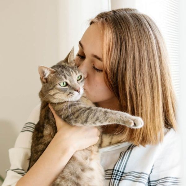 woman kissing her pet cat avoiding phrase hospice vet hates heaing people say last words pets