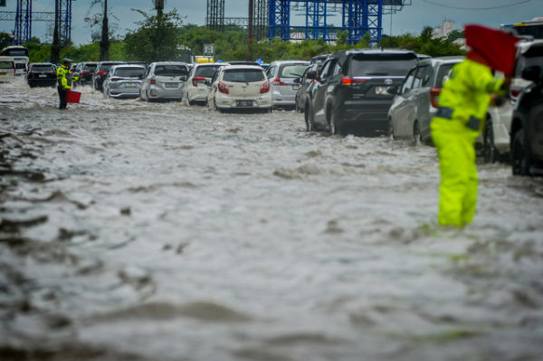 Polisi mengatur lalu lintas kendaraan saat banjir di Jalan Tol Sedyatmo, Cengkareng, Jakarta, Rabu (29/1/2025). Foto: ANTARA FOTO/Putra M. Akbar