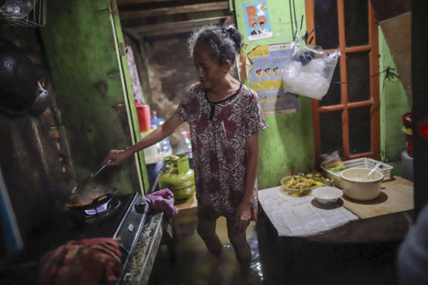 Erni, memasak gorengan saat rumahnya dilanda banjir, Grogol, Jakarta Barat, 29 Januari 2025. Foto: Jamal Ramadhan/kumparan