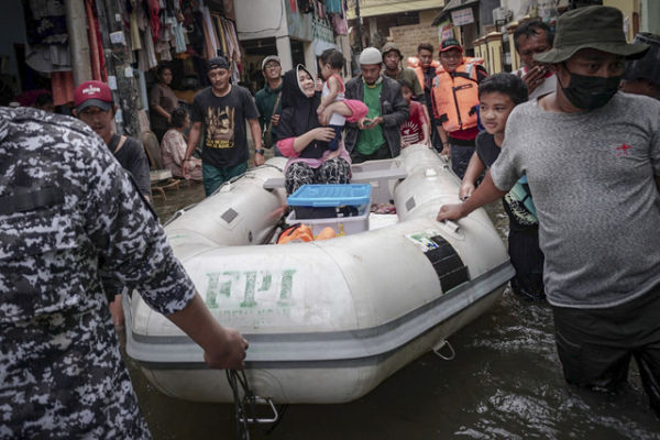 Seorang ibu dan anak menaiki perahu karet saat banjir rob melanda kawasan Lodan pada 7 Desember 2021. Foto: Jamal Ramadhan/kumparan