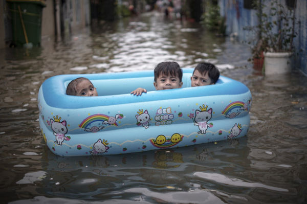 Tiga anak kecil menaiki perahu karet saat banjir rob melanda kawasan Lodan, Ancol pada 7 Desember 2021. Foto: Jamal Ramadhan/kumparan