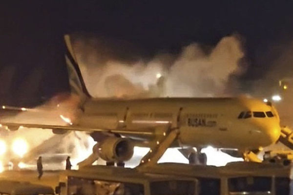 Petugas pemadam kebakaran berusaha memadamkan api yang membakar pesawat penumpang Air Busan di Bandara Internasional Gimhae, Busan, Korea Selatan, Selasa (28/1/2025). Foto: Yonhap via AFP