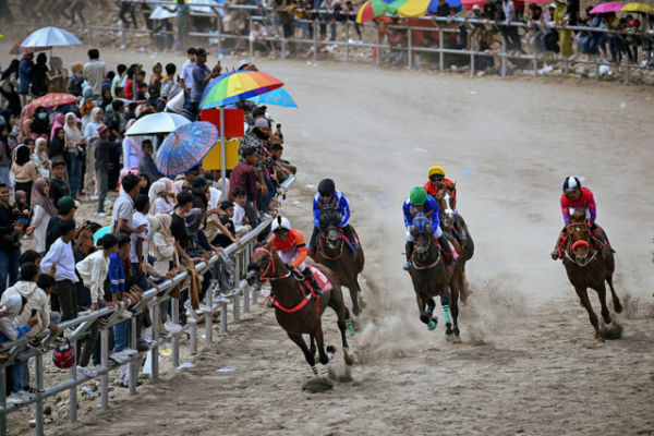 Joki Jawa Barat Jemmy  SH Runtu (tengah) beradu kecepatan dengan joki DKI Jakarta Ended Rahmat (kiri) dalam perlombaan pacuan kuda kelas A-2.200 M PON XXI Aceh-Sumut 2024 di Arena Pacuan Kuda Belang Bebangka, Kabupaten Aceh Tengah, Kamis (12/9). Foto: Arnas Padda/ANTARA FOTO