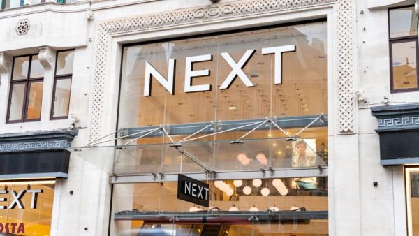 Next logo and store facade in London with a mannequin in leggings posing with one leg straight and the other bent