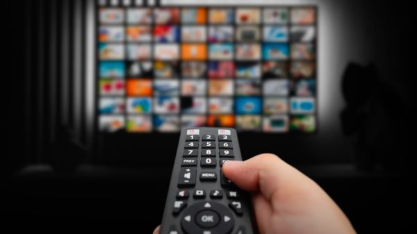 A Person Holding A Smart TV Remote With Several Applications On Screen