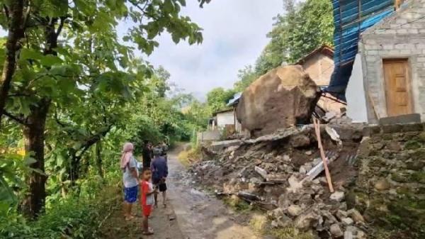 BATU BESAR - Sebuah batu raksasa dengan diameter sekitar 4 meter terjun bebas karena longsor ke rumah milik Narto di Desa Ngilo Ilo, Kecamatan Slahung, Ponorogo, Jawa Timur, Minggu (23/2/2025). Warga menunggu bantuan dari BPBDP untuk melakukan evakuasi batu besar ini