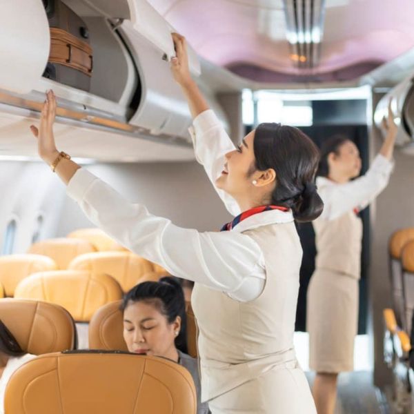 flight attendant putting bag in overhead bin