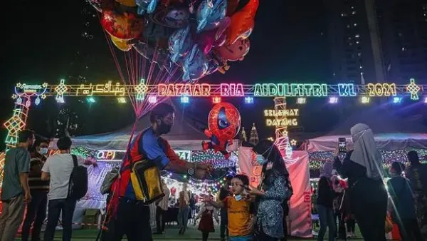 KUALA LUMPUR, MALAYSIA : A man sells balloons to customers at a Ramadan bazaar in Kuala Lumpur, Malaysia. Ramadan bazaars in Malaysia offering various selections of clothing, food, and other religious items to Muslims who traditionally shop for new outfits to usher Eid al-Fitr, known as the 