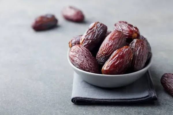 Fresh medjool dates in bowl. Grey background. Copy space