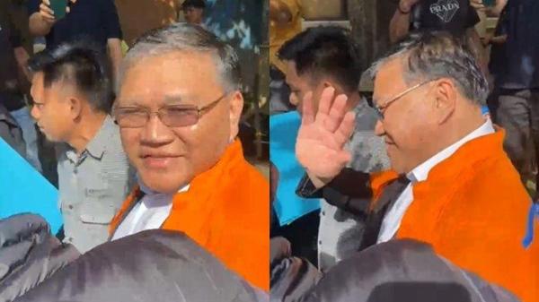 BAJU ORANYE - Pendeta Hein Arina tersenyum dan lambaikan tangan saat digiring ke ruang tahanan Polda Sulut dengan memakai baju oranye atau baju tahanan, Kamis (17/4/2025).