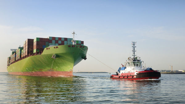 A Tugboat Pulling A Container Ship In Calm Uncongested Waters