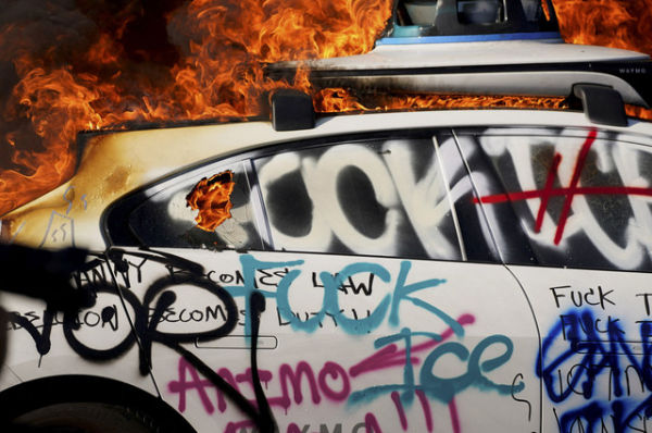 Sebuah mobil swakemudi Waymo terbakar dalam sebuah protes menentang razia imigrasi federal, di pusat kota Los Angeles, California, AS, Minggu (8/6/2025). Foto: David Ryder/REUTERS