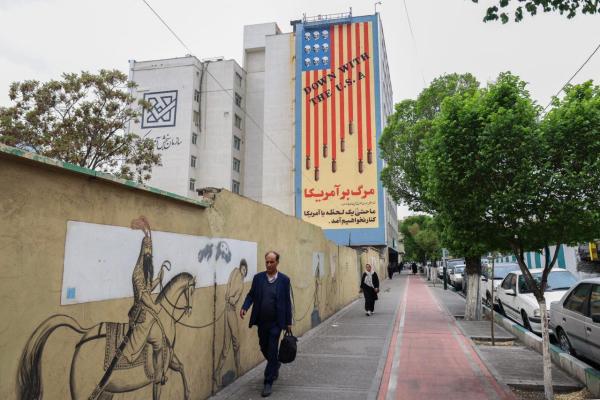 People walk along Tehran's Karim Khan Zand Avenue past a building with a landmark anti-U.S. mural with the slogan "Down with the USA" and skulls replacing the stars on the U.S. flag, Tehran, Iran on April 12, 2025. (AFP Photo)