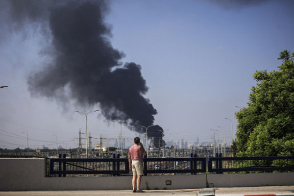 Seorang pria Israel melihat asap yang membumbung tinggi setelah serangan rudal dari Iran, di Herzliya, Israel, Selasa (17/6/2025). Foto: Itai Ron/REUTERS