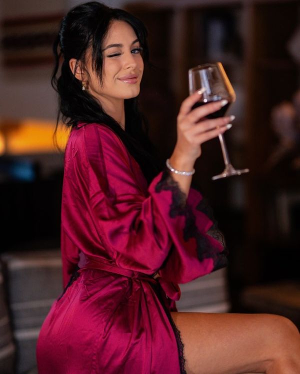 Woman in a silk robe holding a glass of red wine.