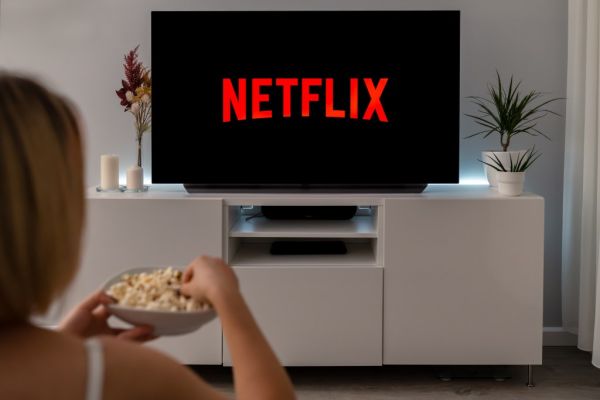 Woman watching Netflix on TV while eating popcorn.
