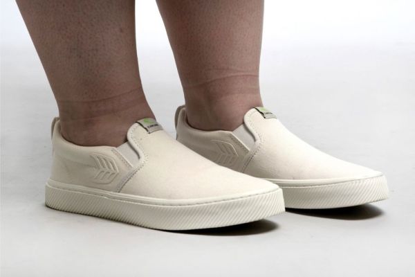 A pair of white slip-on canvas shoes.