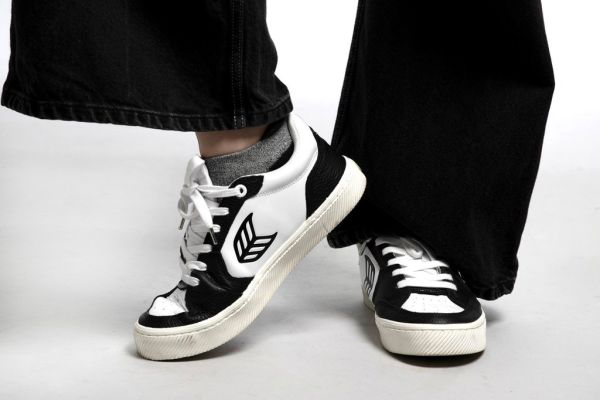 A person standing in a pair of black and white Cariuma skater sneakers