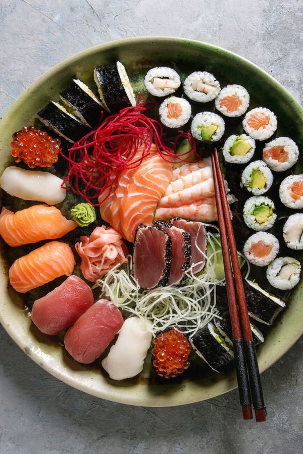 This may contain: a bowl filled with sushi and chopsticks