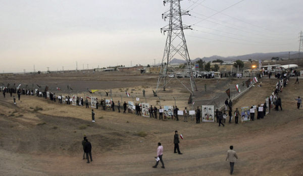 Para mahasiswa Iran membentuk rantai manusia dalam sebuah protes untuk mempertahankan program nuklir negara mereka di luar Fasilitas Konversi Uranium Fordo di Qom, Iran (19/11/2013). Foto: CHAVOSH HOMAVANDI/AFP